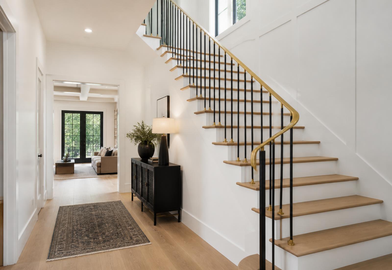 Remodeled white oak staircase with black iron balusters and a brass handrail